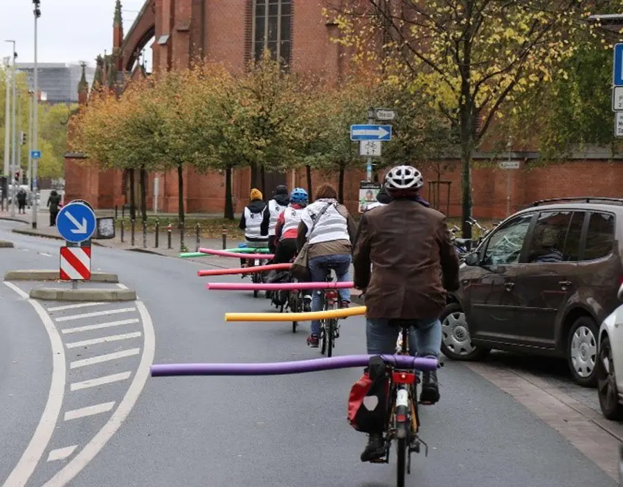 Mit Poolnudeln sorgen Radfahrer für die Einhaltung des Sicherheitsabstands. Eine Gruppe von fünf Radfahrern mit bunten Schwimmnudeln auf den Gepäckträgern als Fahrrad Abstandshalter fährt durch die Stadt und gewährleistet so ausreichenden Sicherheitsabstand.