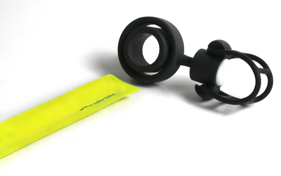Die Montage des Safety Spacers Fahrrad Abstandshalter: Das gestreckte Schnappband wird  vor die Öffnung zwischen den Ringen der schwarzen Halterung gelegt. Die Wölbung des Bandes muss der Rundung der Öffnung entsprechen.