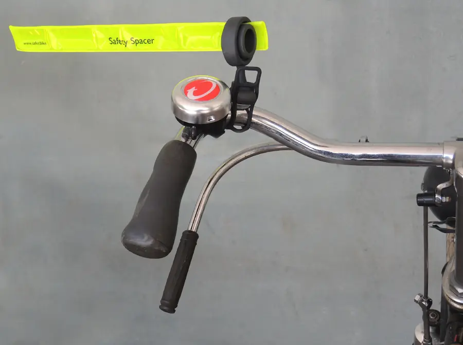 Um nicht dem Bremshebel an diesem Oldie-Rads im Weg zu sein, wurde der Halter des Safety Spacers Fahrrad Abstandshalter vertikal nach oben ragend montiert. Das leuchtend gelbe, hochreflektierende Schnappband ragt wie bei allen anderen Lenkerformen im rechten Winkel auf die Fahrbahn und dient so als Fahrrad Abstandshalter für den Sicherheitsabstand.