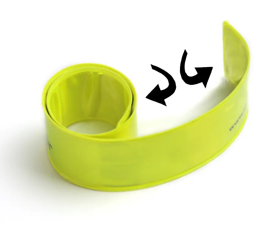 Das hochreflektierende Schnappband des Safety Spacer Fahrrad Abstandshalter wird, wie durch die Pfeile angezeigt, mit zwei Händen auseinandergerollt.